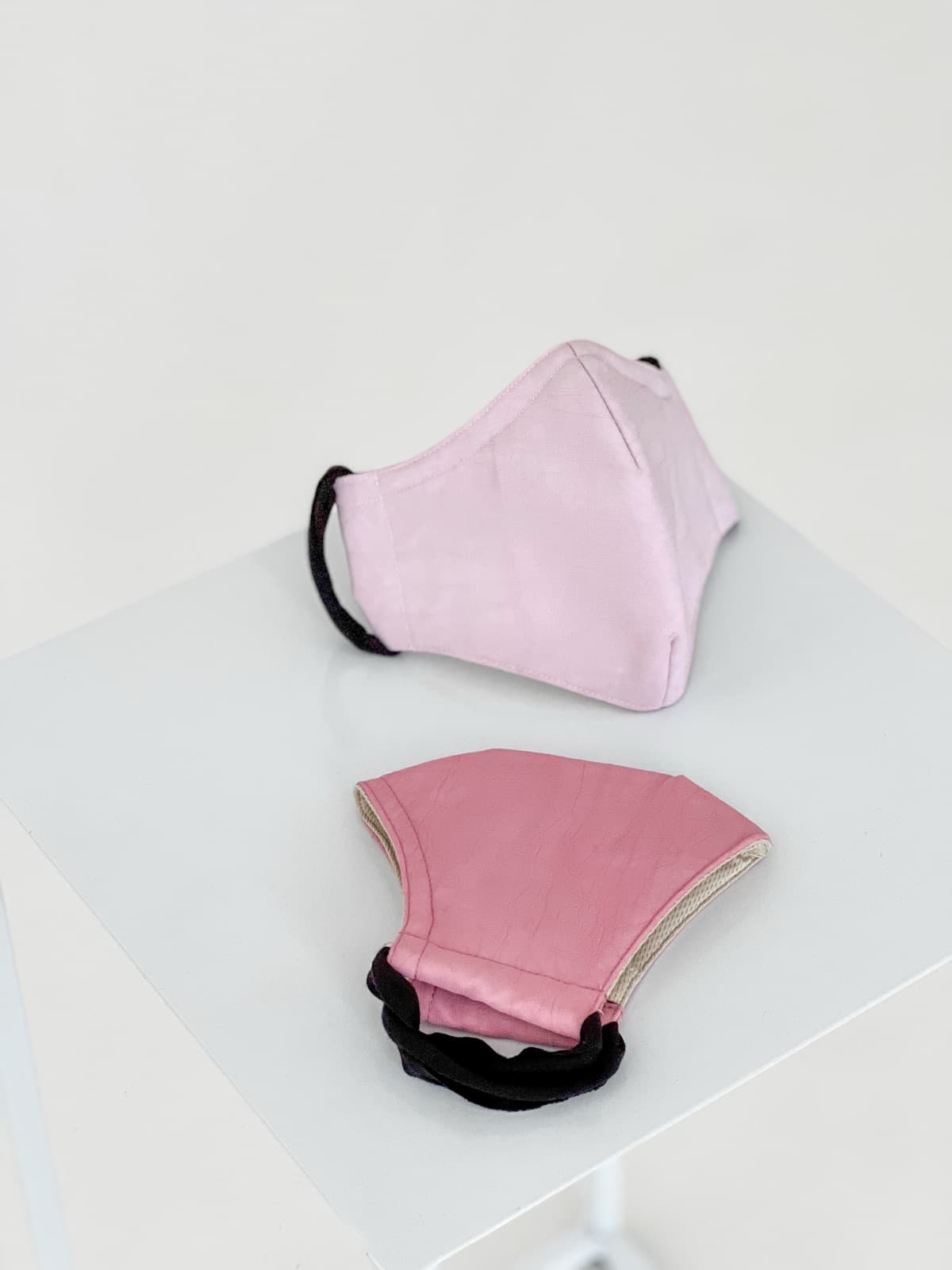 Two pink masks on a white plinth