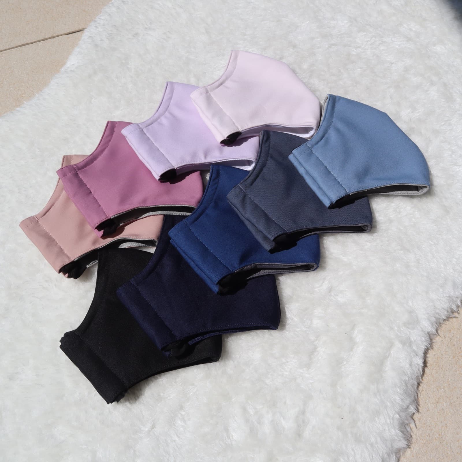 Ten Classic+ masks in pastel and solid colours fanned out on white fur